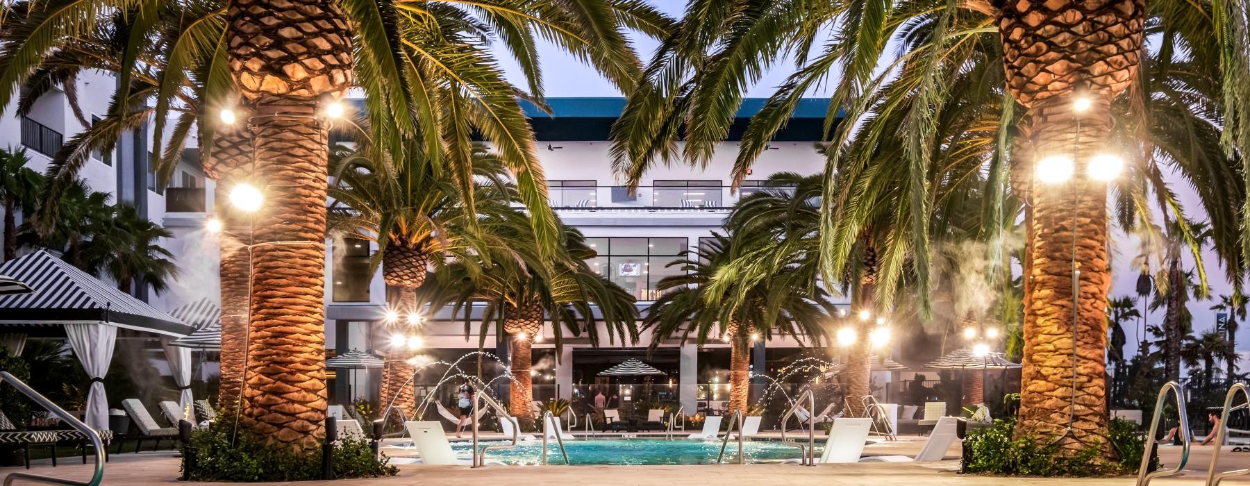 a pool with palm trees and a building in the background