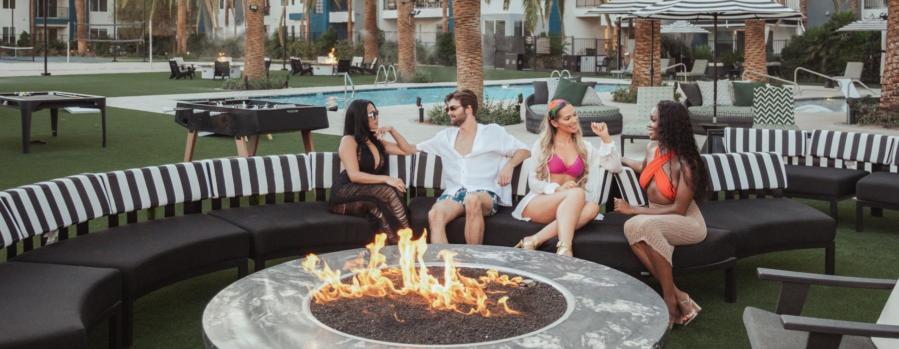 a group of people sitting around a table with a fire in it